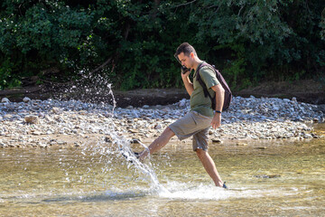 A young man dancing on the water on a sunny day, on a mountain river. © NAIL BATTALOV