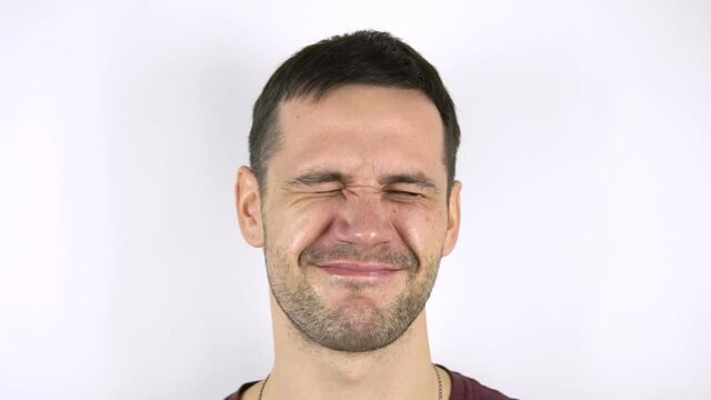 Fresh herring hits the face of a young attractive guy. Funny young guy is slapped in the face with wet fresh fish.