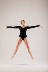 Modern style ballet dancer posing on studio background