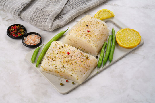 Raw halibut fish fillet on cutting board on white background 