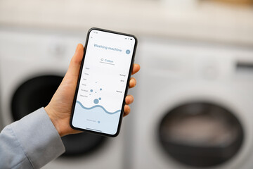 Woman controls washing machine with a smartphone