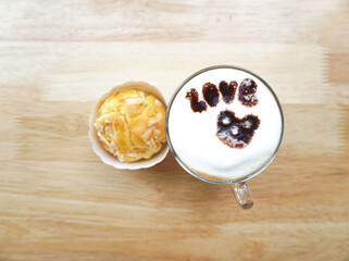 An Almond muffin with a hot mocca with a latte art with the word 
