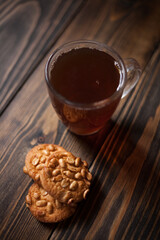 Peanut cookies, and a mug of fragrant tea on a wooden background. With space for your text. 