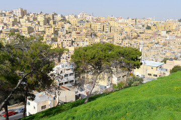 Skyline of Amman, Jordan in the Middle East. Densely populated area in a hill with multiple low buildings in yellow color and of simple architecture.