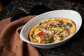 Omelet with tomatoes and cheese for breakfast in a white dish