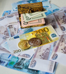 two bitcoin coins lie on a background of various money, there is a chest with dollars next to it