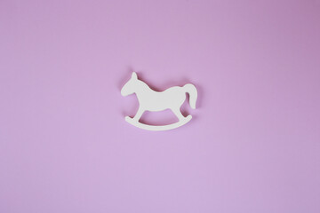 Baby accessories on lavender background, flat lay. Composition with baby accessories and space for text. Baby toy, white baby horse