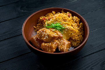 Pan-Asian Street Food - Sweet and Sour Chicken Garnished with Rice, served in a bowl on a wooden background. Wok rice with chicken. Asian food. Selective focus