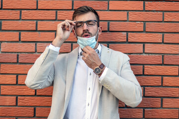 Portrait of the young man standing in front of the brick wall with a face mask.