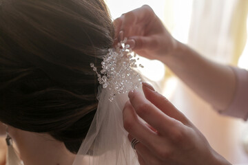 bridesmaid puts on the bride's hair a veil