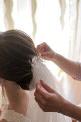 bridesmaid puts on the bride's hair a veil