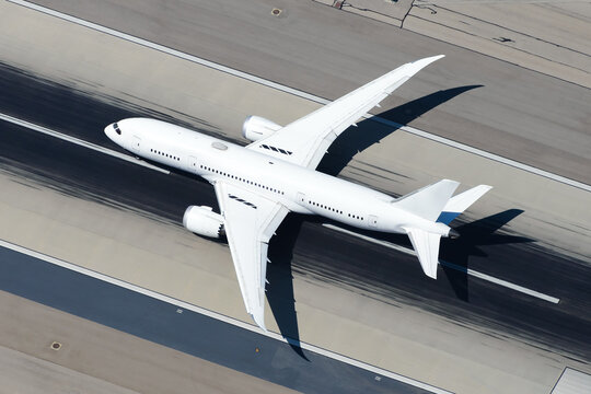 Unidentified aircraft departing international airport runway. White untitled airplane aerial view. Large widebody plane.