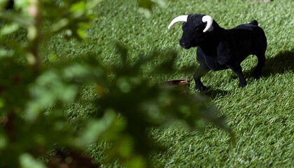 Vista de un toro de souvenir en un campo simulado con un cubo de agua y la sombra de un arbol...