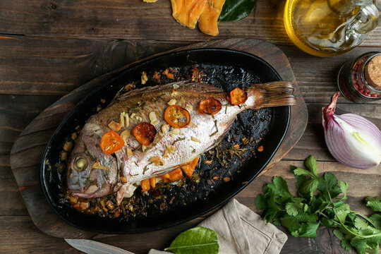 baked or roasted porgy in the black cast iron brazier with oil and cilantro and spices