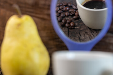 cup of coffee and beans on wooden table seen from mirror