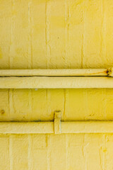 A painted yellow brick wall with pipes