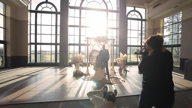 Wedding photographer taking photos of a newlywed couple posing at the alter. HD 24FPS.