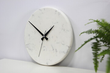 Fototapeta na wymiar Decorative white marble wall clock, Modern analog wall clock and black watch dial.