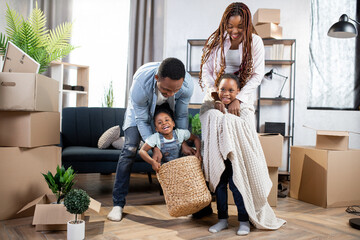 Smiling african family playing at new modern apartment