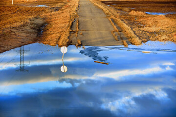 Road is flooded with stop sign almost submerged and reflection in the water