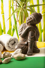 vista de un bodegón de un budha sobre un fondo de bambús con toallas y unas piedras