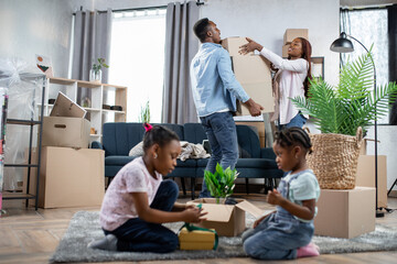 Afro couple packing boxes while kids playing on floor