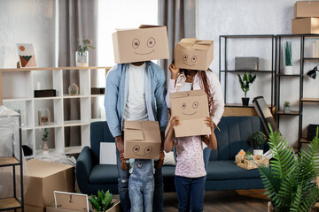 Parents and kids with boxes on heads standing at new house