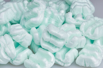 Colorful polystyrene foam chips on a white background. E shape packaging filler cushioning material, which is used for fragile parcel 