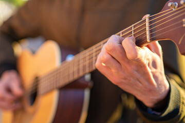 Mano de un guitarrista poniendo un acorde en una guitarra acústica de madera