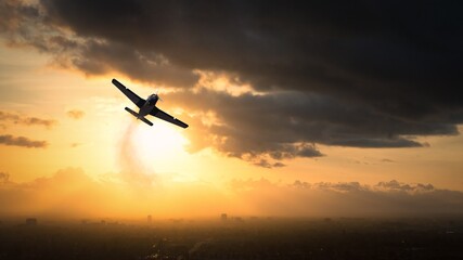 Silhouette of a World War II aircraft flying over a city at sunset, USA