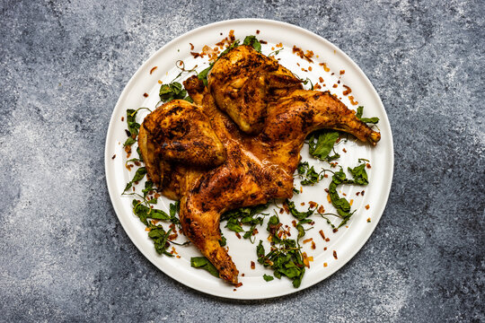 Georgian pan fried chicken tabaka with fried coriander leaves and chilli flakes