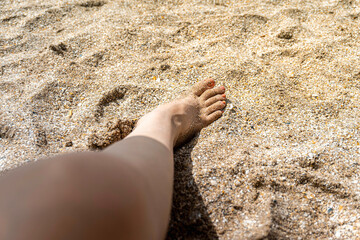 Woman's feet on the sand on a beach.
