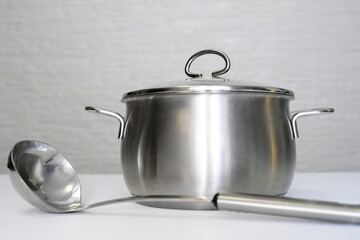 Stainless steel pot, stockpot and a ladle on white table, eco friendly kitchen utensils without harm, harmless safe for people