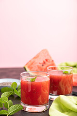 Watermelon juice with chia seeds and mint in glass on a black and pink background with green textile. Side view,  selective focus, copy space.