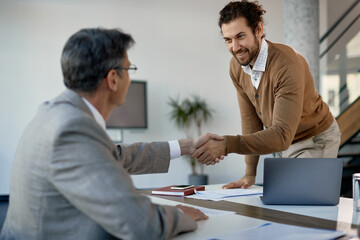 Young happy businessman handshaking with executive manager on meeting at corporate office.