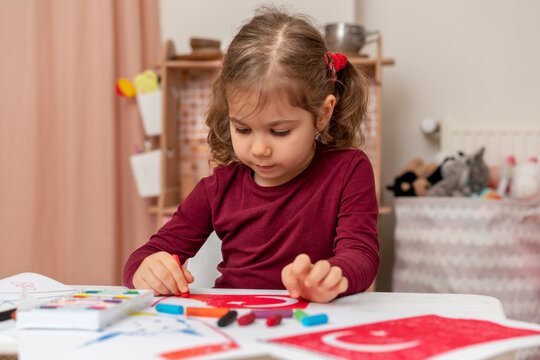 Portrait of small baby girl painting at home. Cute little child drawing Turkish flag picture. Turkish National Sovereignty and Children's Day or Commemoration of Atatürk Youth and Sports Day concept.