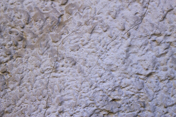 Plastered rough wall with two cracks. Textured city surface background. Grey decorative backdrop. Copy space for text. Uneven old abstraction.