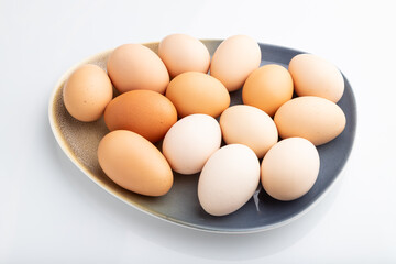 Pile of colored chicken eggs on plate isolated on white background. side view.