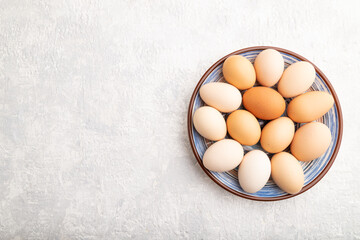 Pile of colored eggs on plate on a gray concrete background. top view, copy space.