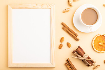 Fototapeta na wymiar Composition with wooden frame, almonds, cinnamon and cup of coffee. mockup on orange background. top view, copy space.