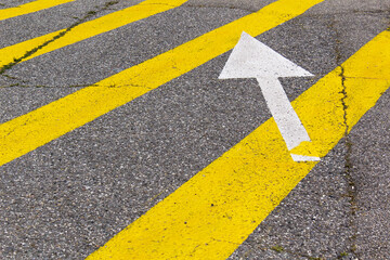 Grey asphalt highway drive road with yellow lines and white arrow 