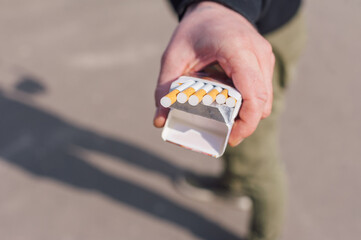A man holds a pack of cigarettes in his hands.