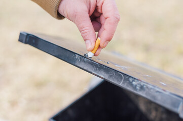 A man puts out a cigarette in the trash.