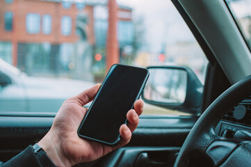 A man uses a smartphone in a car while driving.