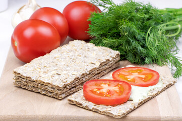 Healthy food. Diet. Crispbread with garlic sauce and tomato on a cutting board. Rye bread rolls. Vitamins. Parsley