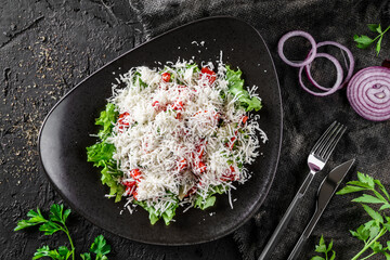 Gourmet appetizing vegetable salad with cheese, salad leaves and parsley. Shopsky Salad in a bowl over a dark background, top up view. Concept of healthy eating