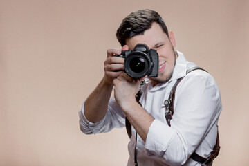 Close up portrait of photographer taking pictures with digital camera on brown background