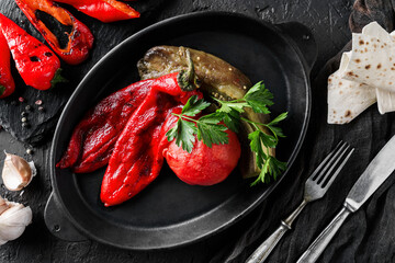Freshly grilled vegetables, red pepper, and eggplant on a pan over a dark background. Barbecue food, vegan, top view
