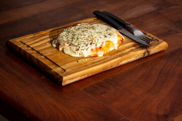 individual pizza with cutlery, on wooden board.