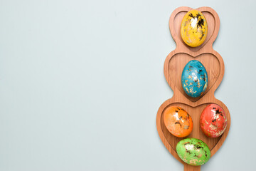 Five Easter eggs lie in a plate with a heart on a delicate background. Postcard with eggs on a light blue background. Layout for Easter.